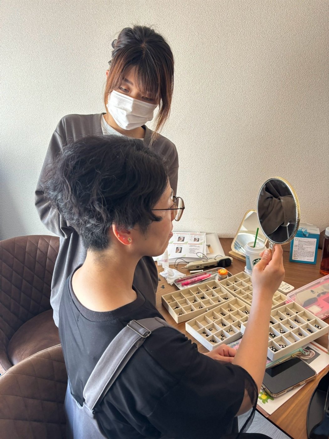 鏡を見ながらフランス式耳つぼジュエリーの仕上がりを確認しているところ